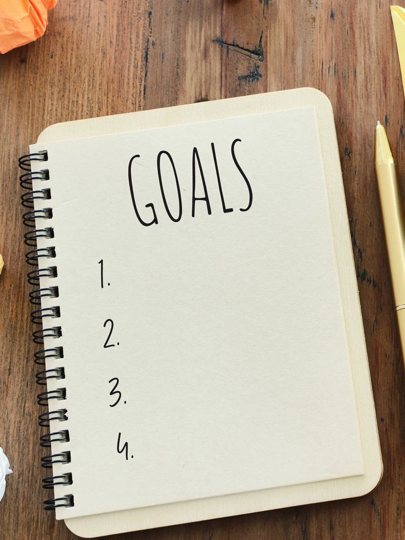 Goals 1-4 written on an A5 notebook